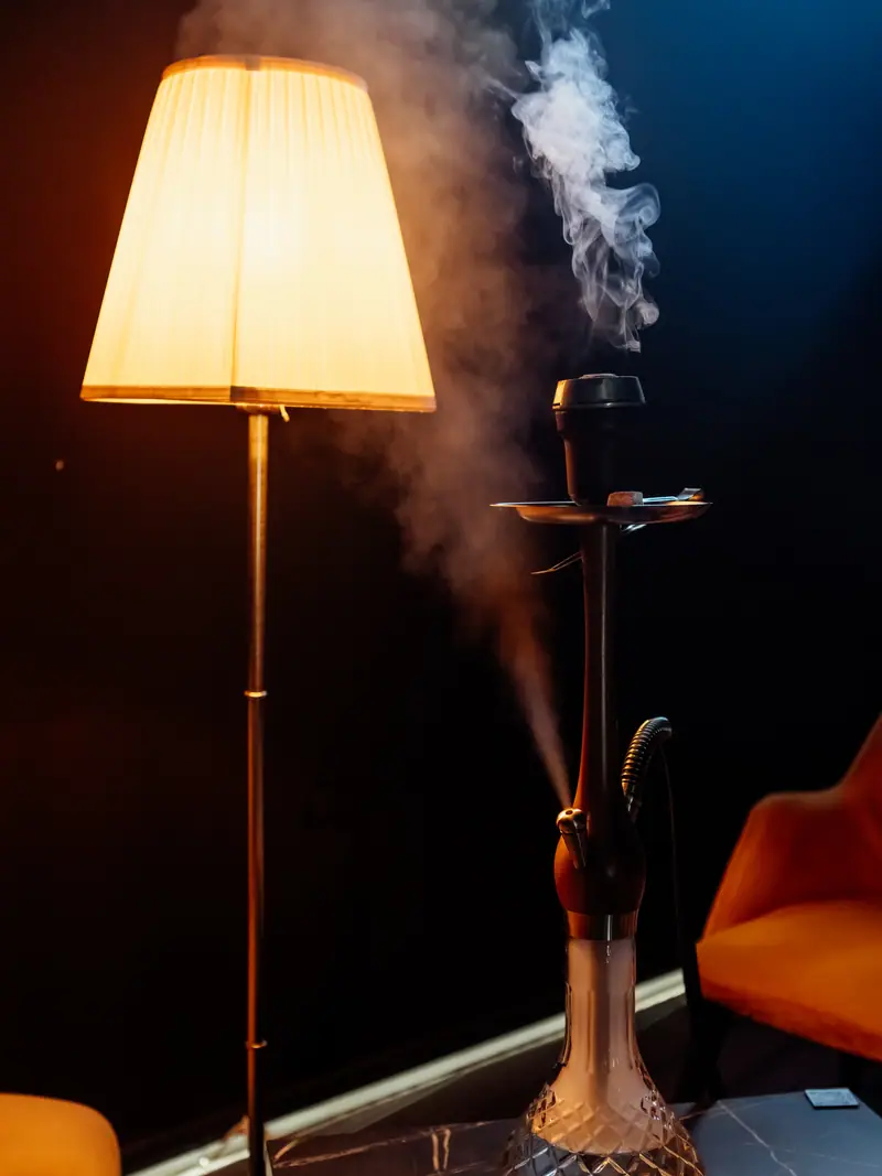 Fum de narghilea în lumina caldă a unei lămpi